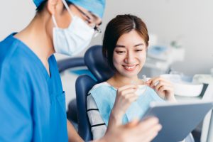 デジタルタブレットを備えた患者に歯のX線を説明するアジアの歯科医